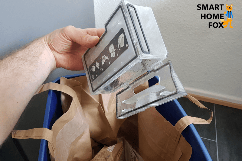 Der mobile Staubbehälter wird per Hand über einem Mülleimer ausgeleert